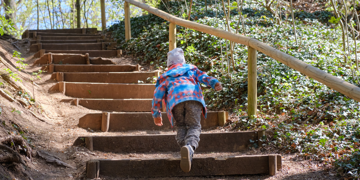 A young child running up some stairs in an outdoor setting. 