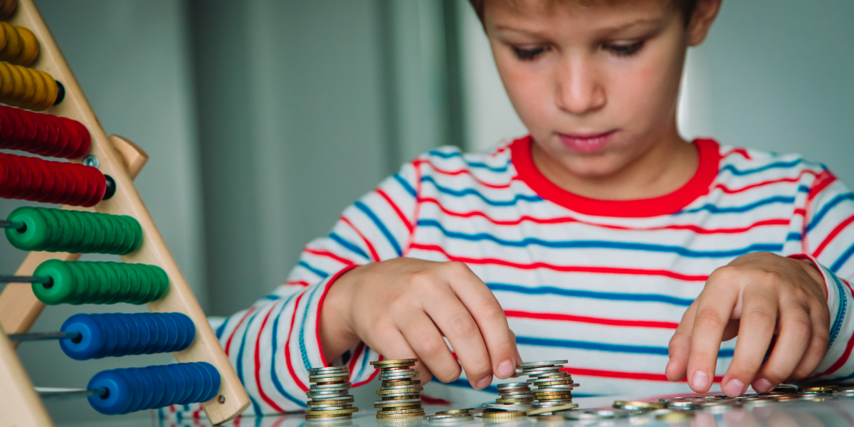 A young boy counting a pile of coins. 