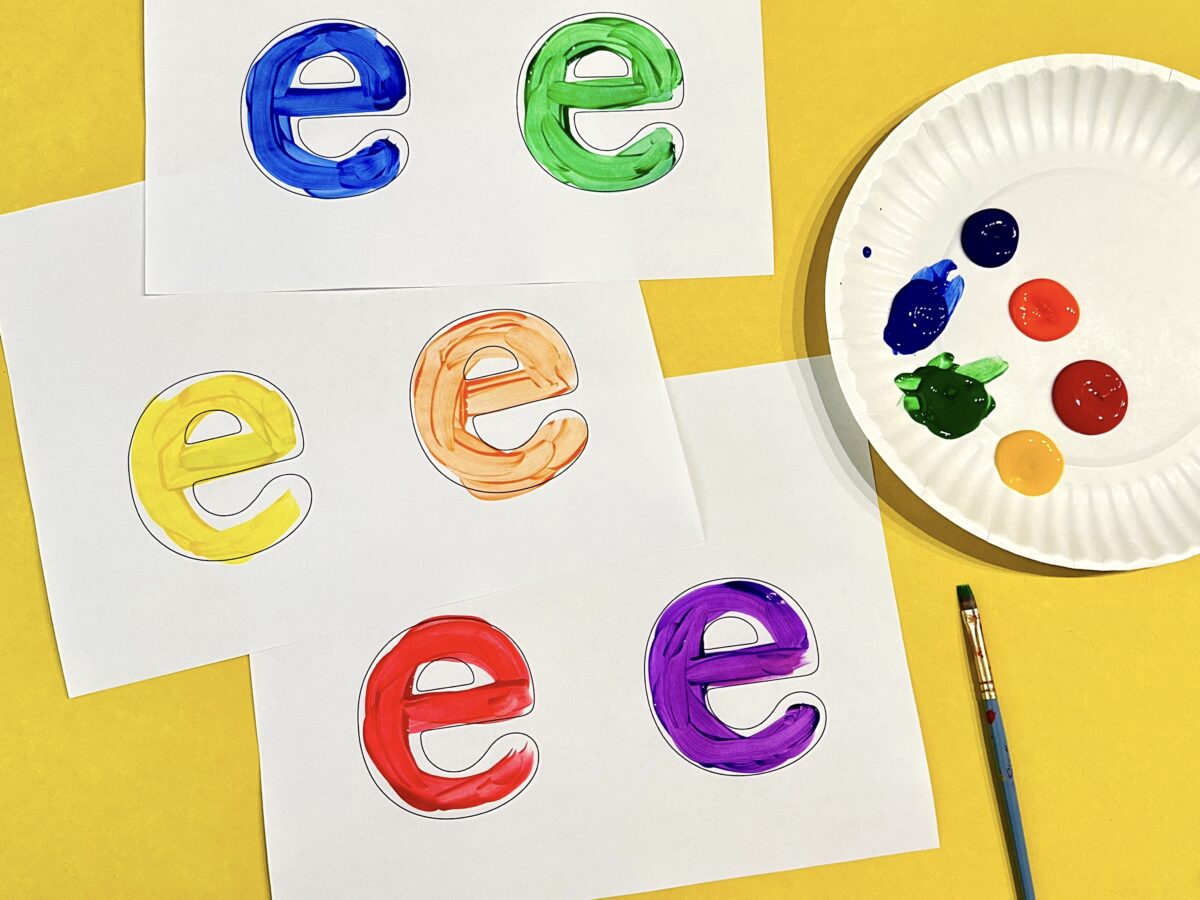 Six colorful small letter e's painted on white sheets of paper. 