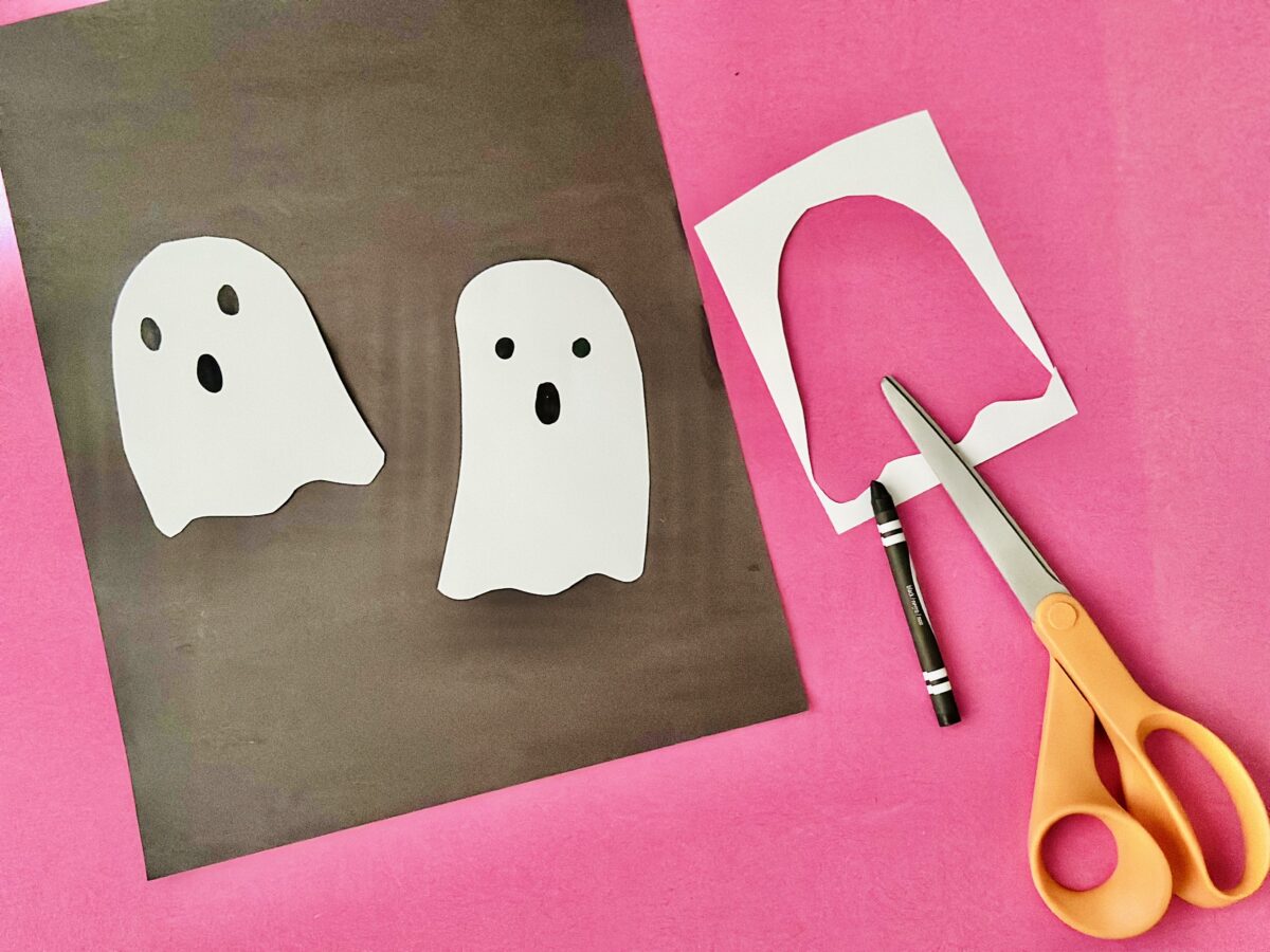 Ghosts cut from white construction paper laid on a brown and pink background. Letter g craft from ABCmouse.com