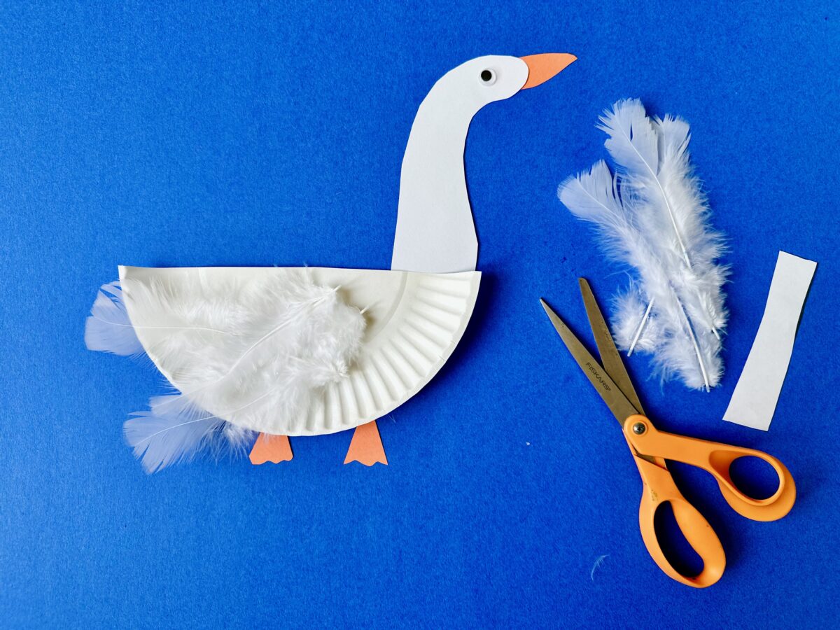 A goose made from a white paper plate, feathers, and construction paper. On a blue back ground. Letter g craft from ABCmouse.com