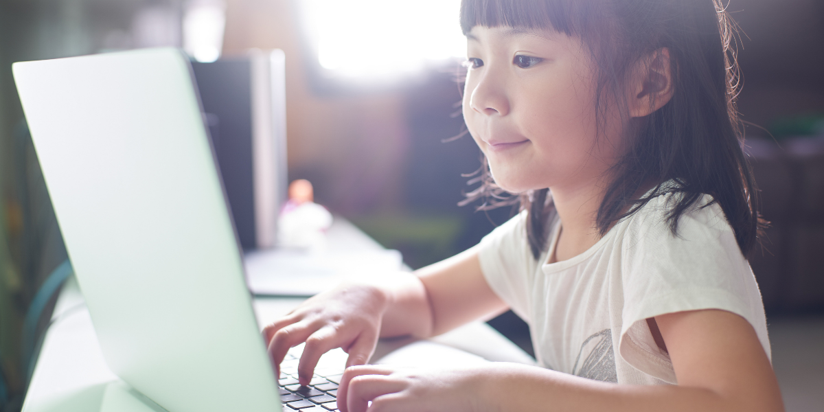 A young girl playing spelling games on a computer. 