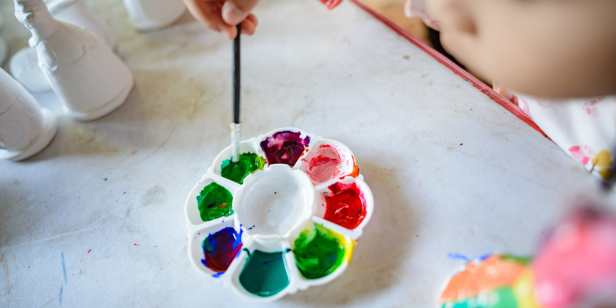 A child mixing paint in a painters pallet. 