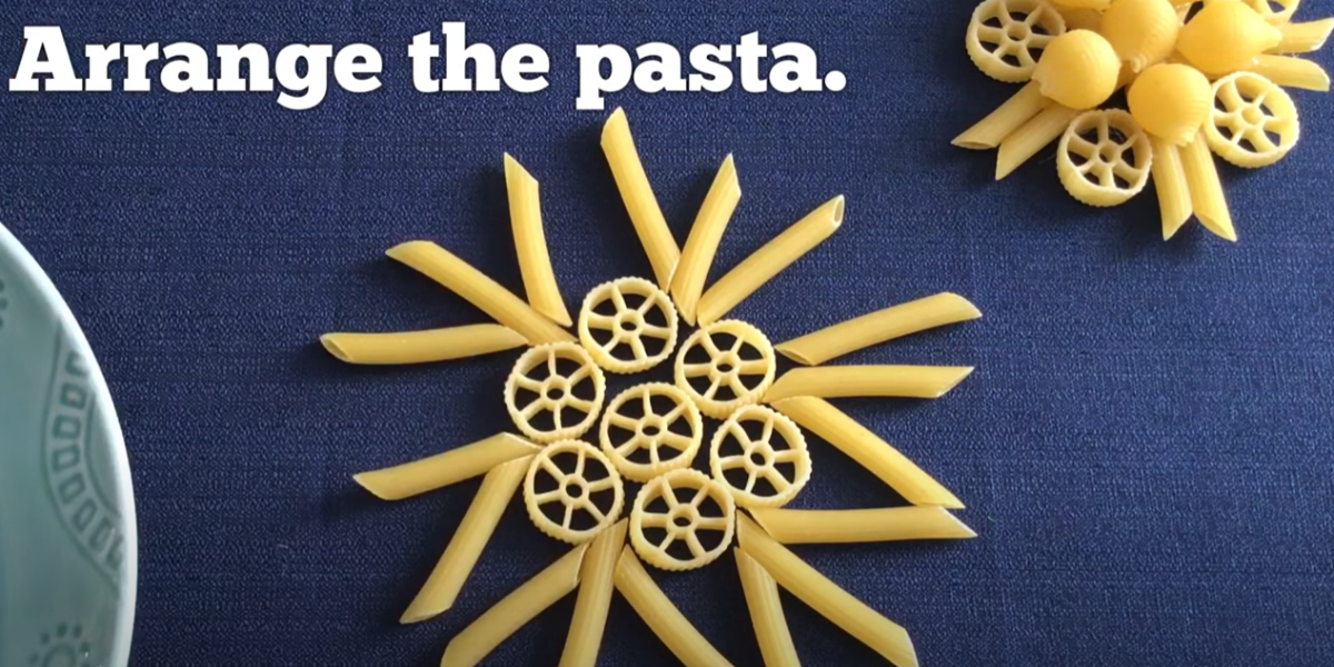 Arranging different shapes of pasta in to a pattern that makes it look like a snowflake. 