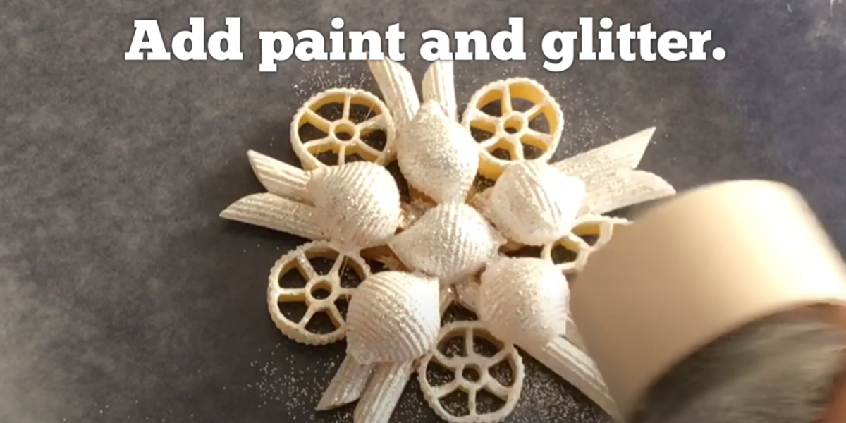 Adding glitter to a pasta snowflake ornament. 