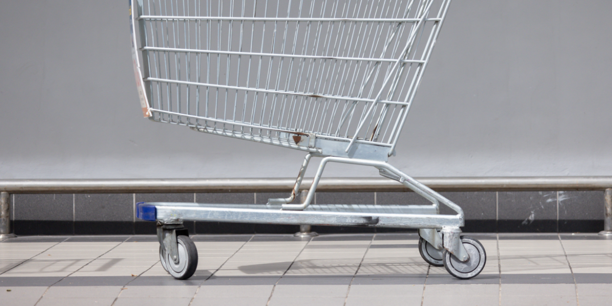 A silver shopping cart with 4 wheels. 