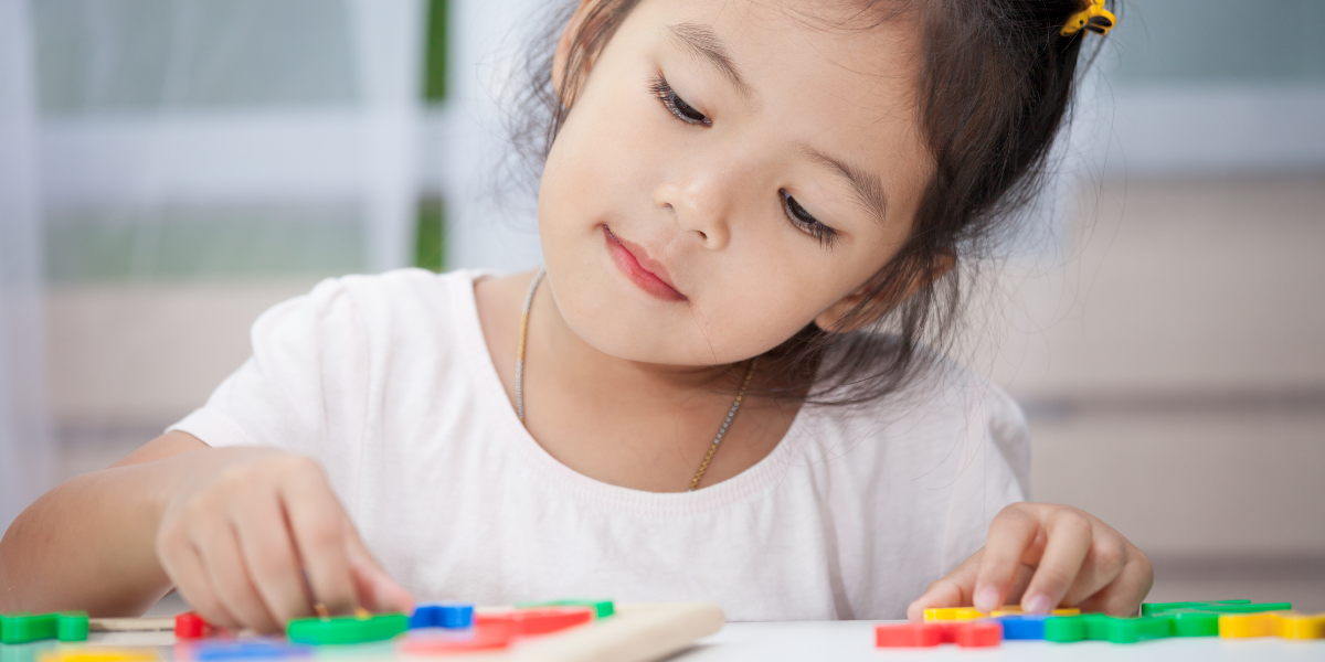 Young girl playing with colorful magnetic letters. 