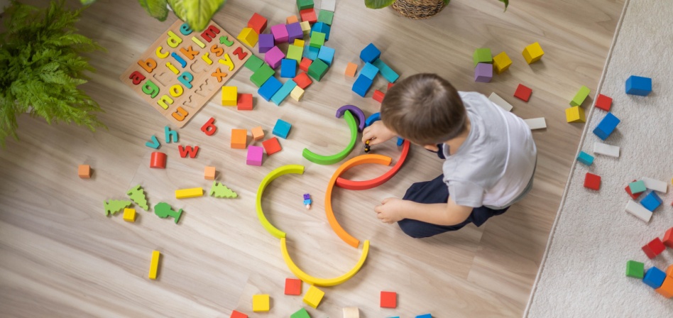 Young boy playing with colorful blocks on the floor. 