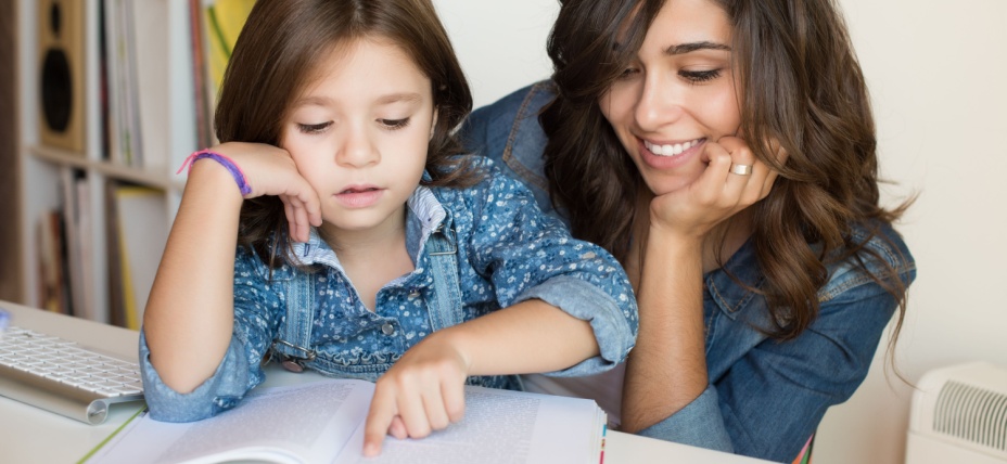 A young mom reading with her daughter helping her learn how to blend words for phonics. 