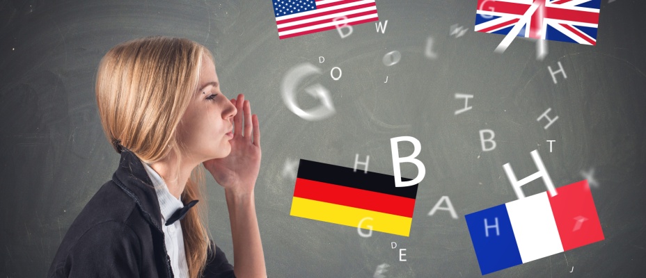 A side view of a young girl with her hand up to her face looking towards the chalkboard with international flags and letters floating. 