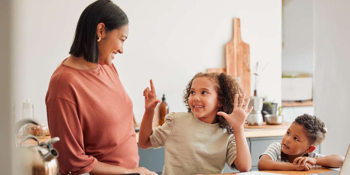 Mother and daughter learning math together while brother watches. 