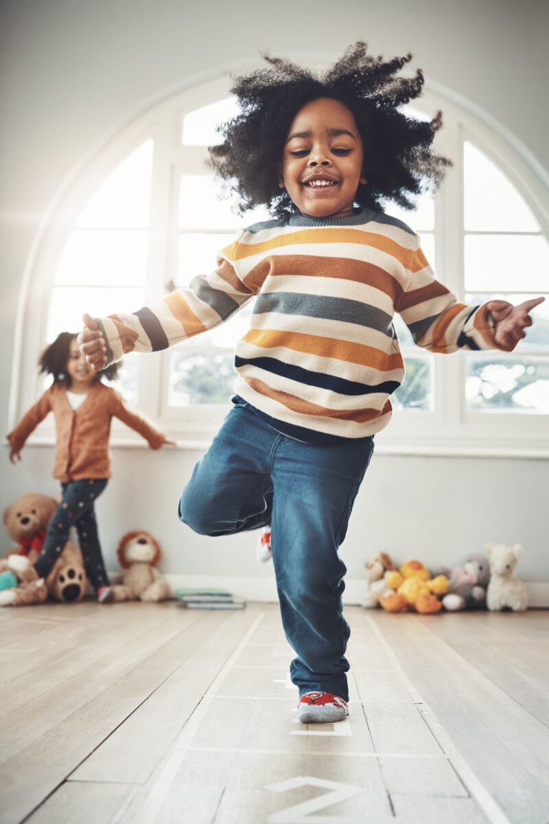 A young girl hopping with one foot on numbers that are taped to the floor. 