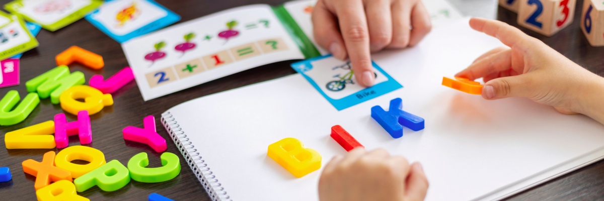 Colorful magnetic letters spelling the word 'bike' arranged on a white sheet of paper, matching the word shown on a flashcard.