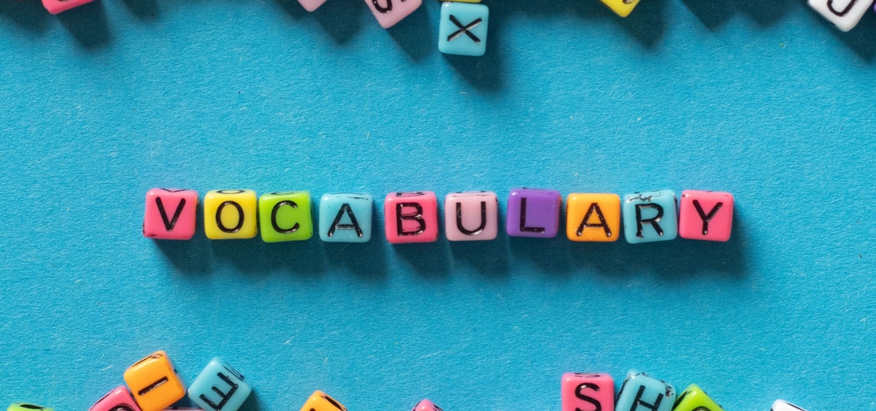 The word vocabulary written in colorful beads across a teal background. 