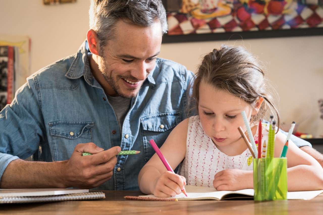 A father and his daughter writing in a notebook together. 