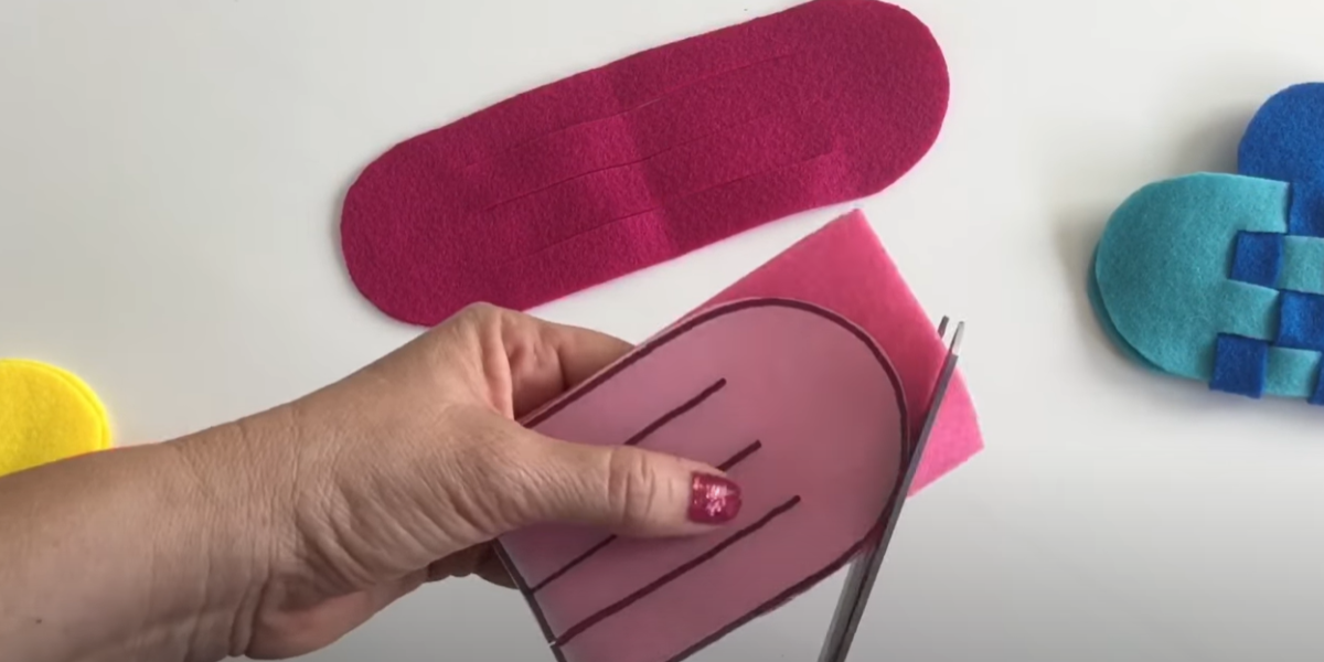 Using a printable pattern to cut a piece of felt out to make a woven heart craft. 