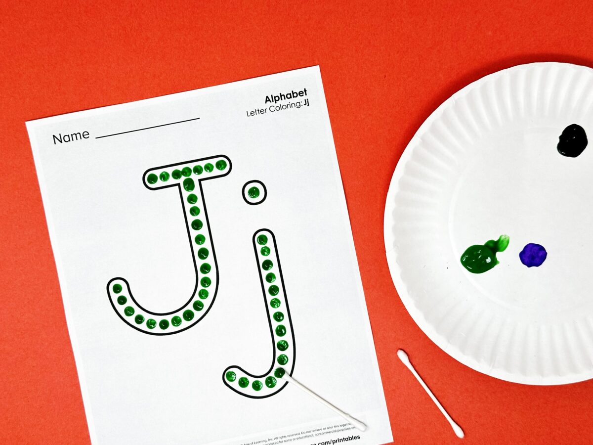 A letter J worksheet painted with green dots using cue tips.  