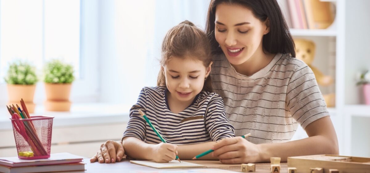 A mother and daughter writing a list together learning at the kitchen table. 