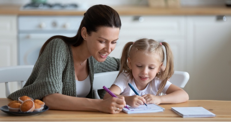 Mother and daughter writing prefixes in her notebook at the kitchen table. 