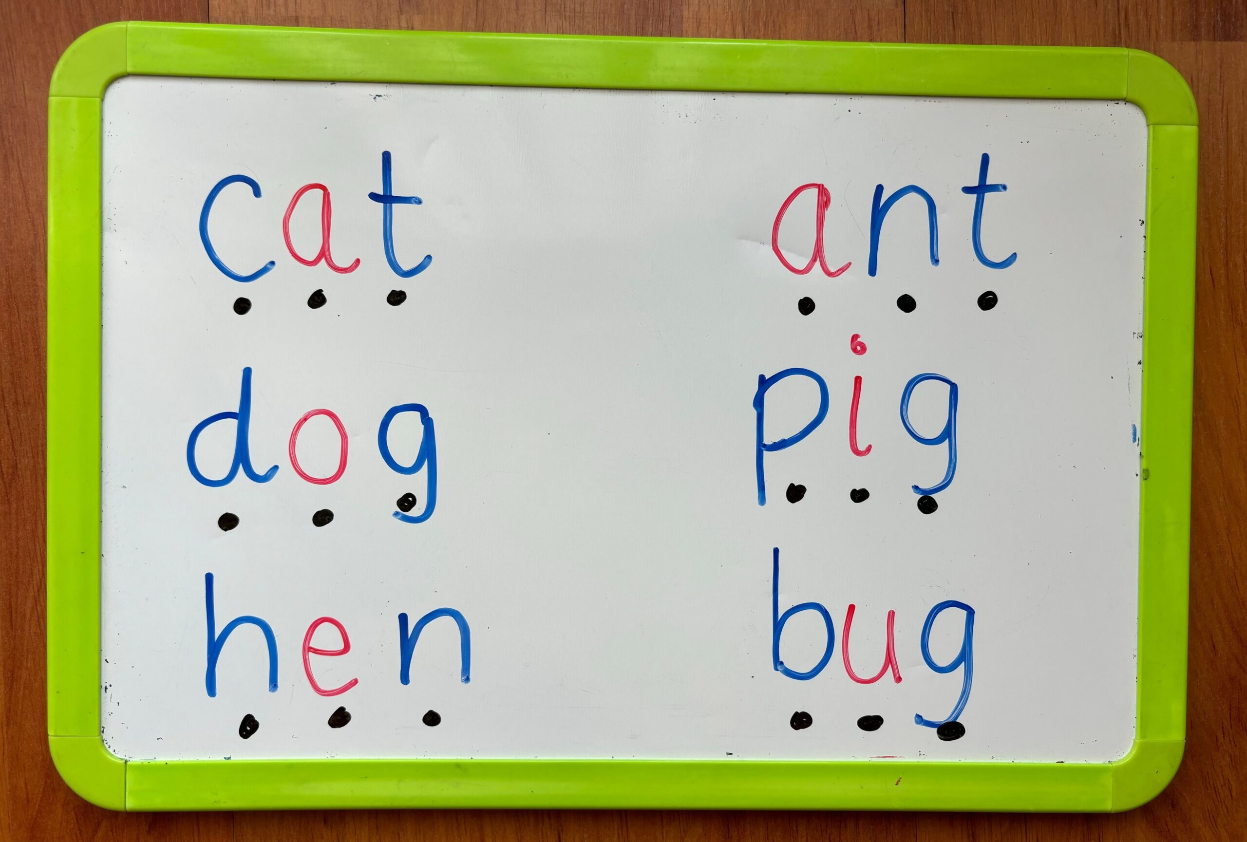 A whiteboard of cvc words in blue and red letters. 