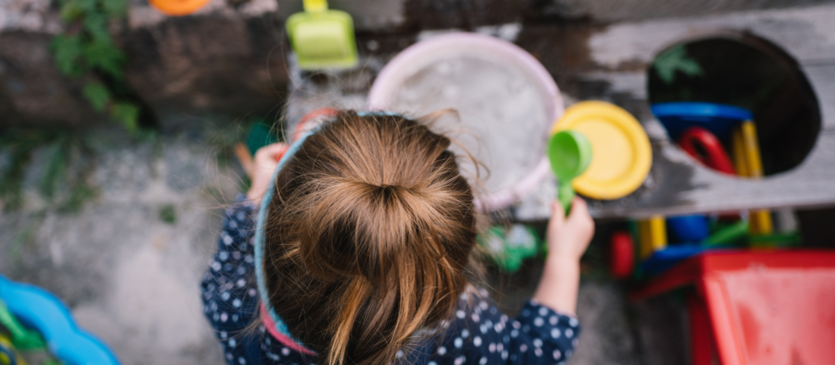 A young girl playing in a mud kitchen for a fun outdoor activity. 