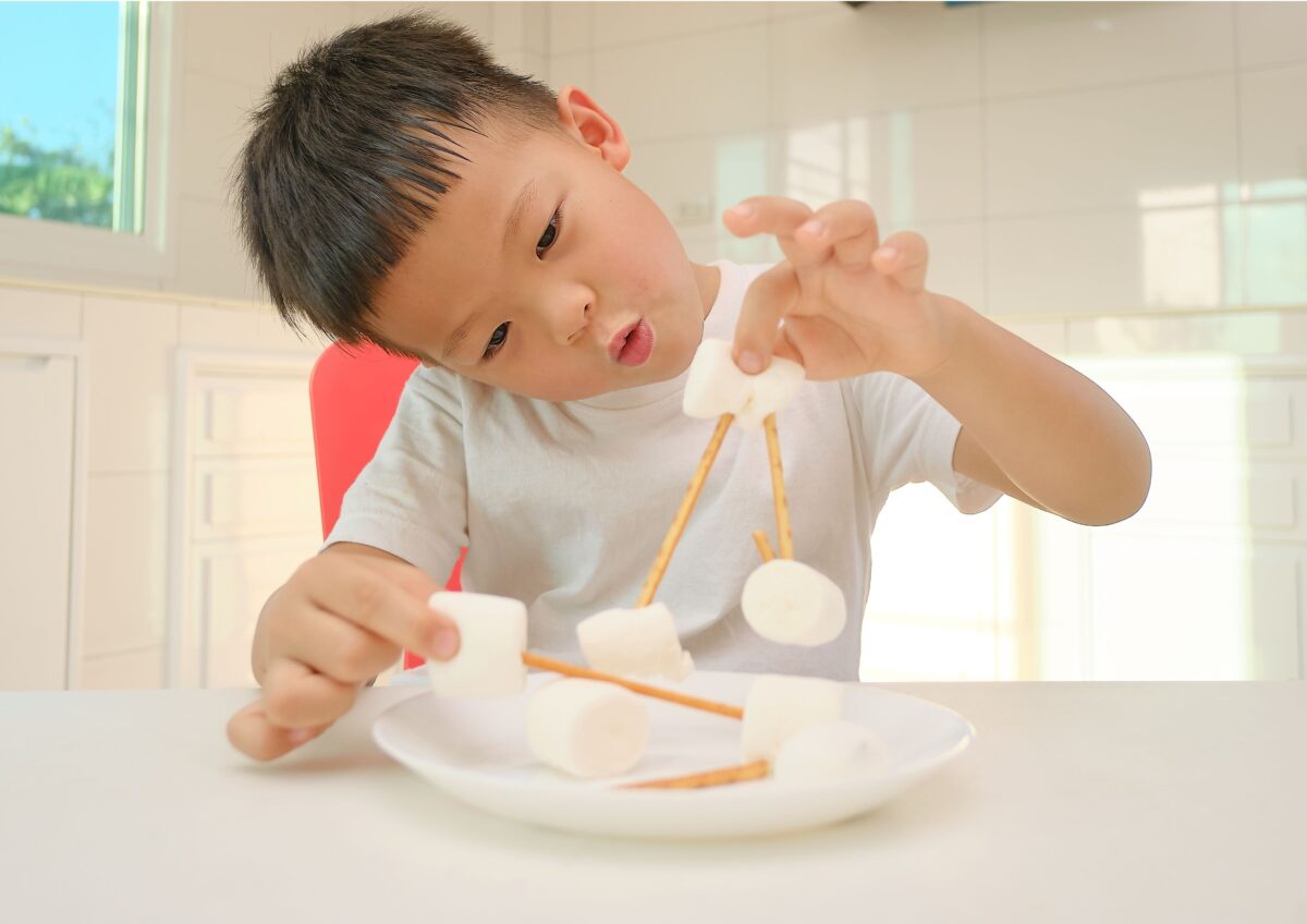 A young boy making a marshmallow tower as a fun science activity. 