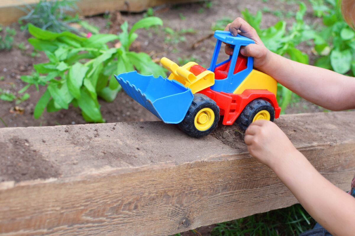 A colorful toy truck being pushed by a child's hands. 