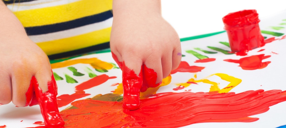 Child finger painting with red paint. 