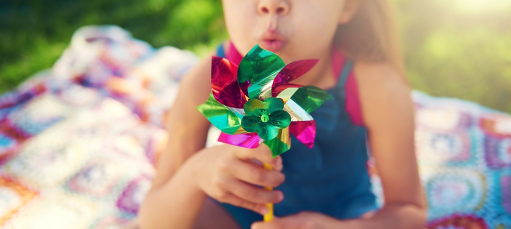 Young girl blowing on a pinwheel. 