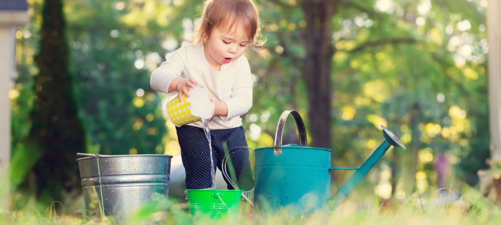 Young child poring water into different buckets. 