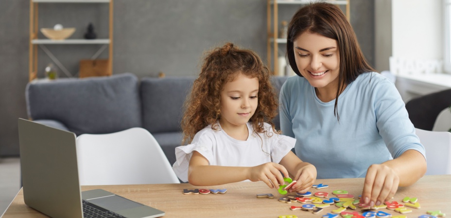 Mother and daughter playing with colorful letters together. 