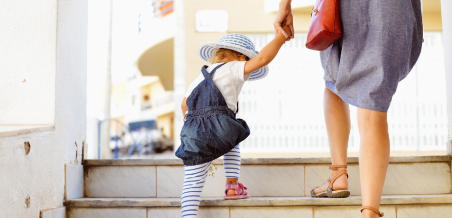 A young mother holding her child's hand while counting the steps as they ascend. 