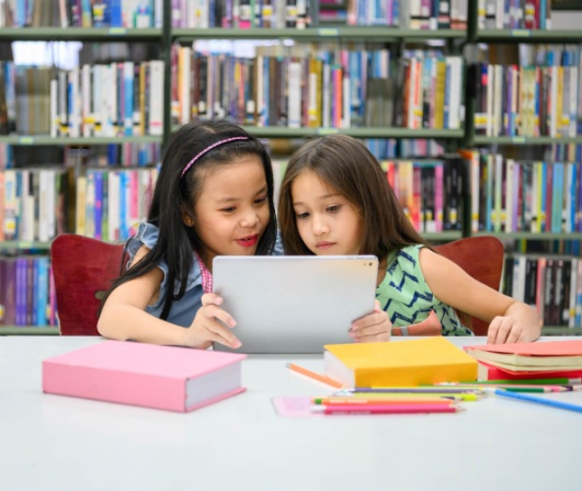 Two girls reading together in their local library. 