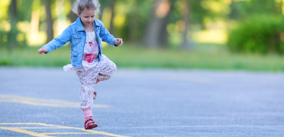 A young girl playing hop scotch. 