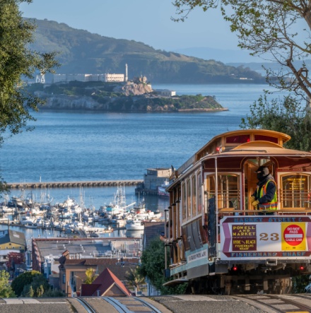 A San Francisco trolley driving down the road towards the bay. 