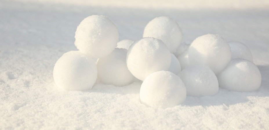 A pile of white snow balls sitting in the snow. 