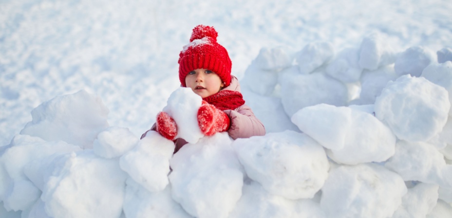 A child playing in the snow making a fun snow sculpture for a winter activity. 