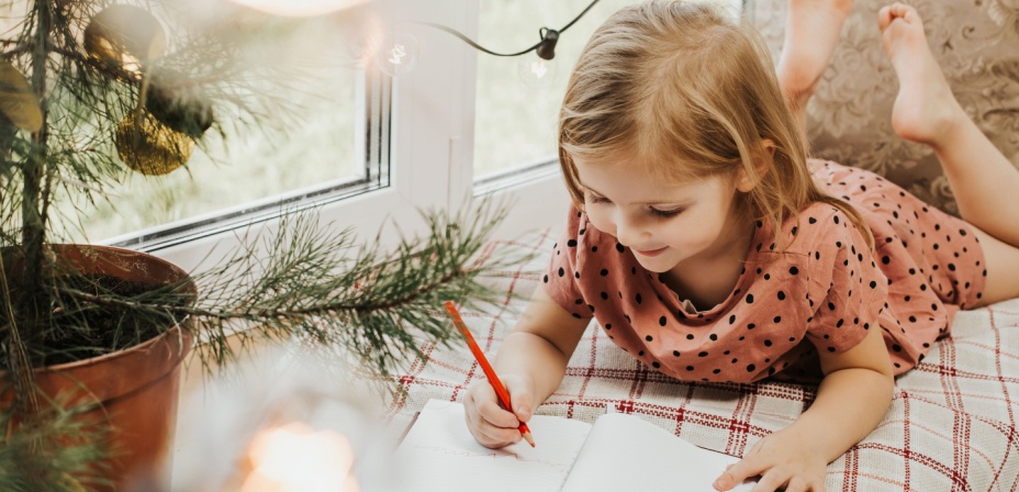 A young girl happily writing a winter poem for a fun indoor winter activity. 