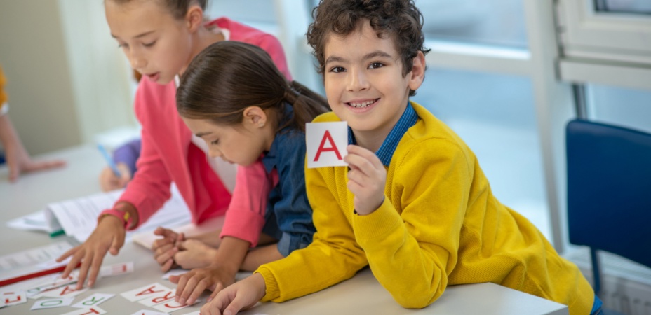 Children working with letter flashcards learning bow to blend letters together to read. 