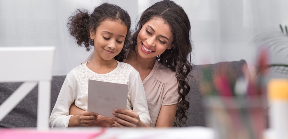 A mother and daughter enjoying reading a sheet of paper together. 