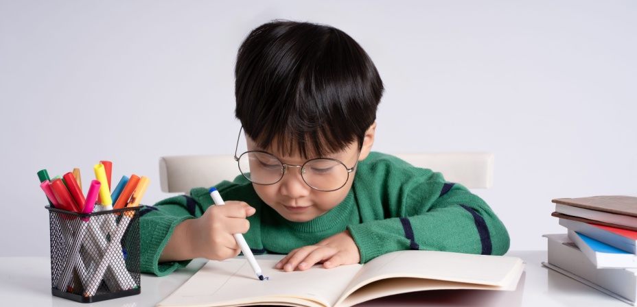 A young boy drawing in a book. 