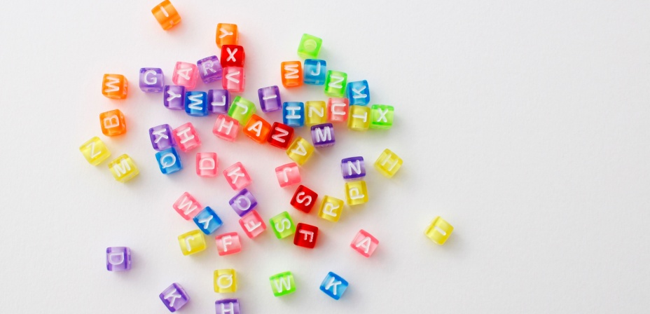 Colorful letter beads spread out over a white background. 