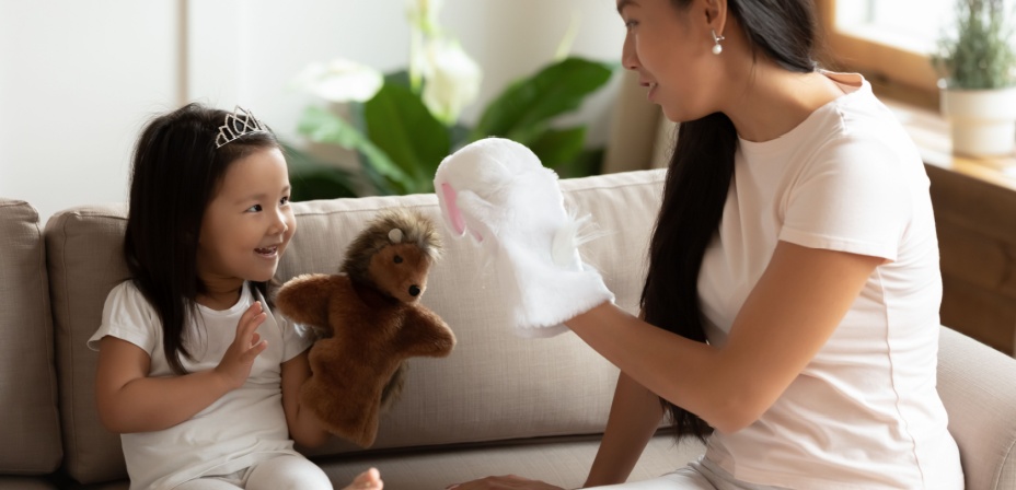 A young mom playing with hand puppets with her daughter. 