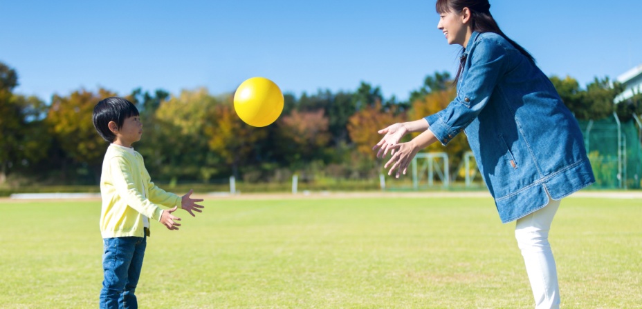 A young mother throwing a ball to her young toddler boy. 