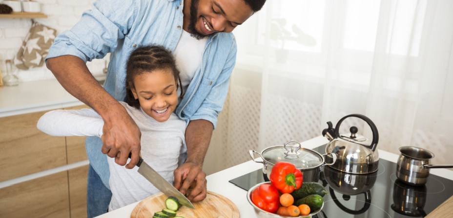 A young daughter cooking with her dad. 