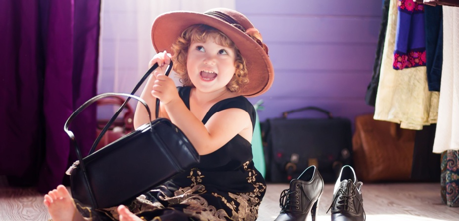 A cute young toddler dressing up in her mommies clothes. 