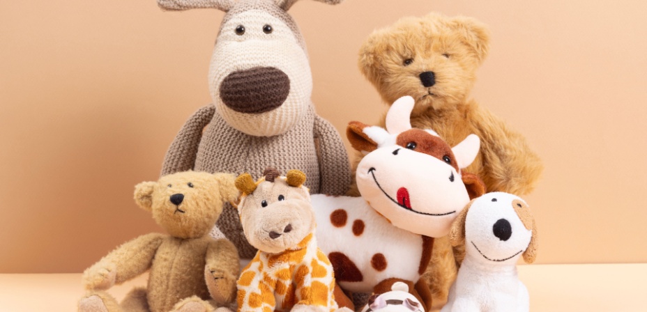 A collection of cute stuffed animals sitting in front of a peach background. 