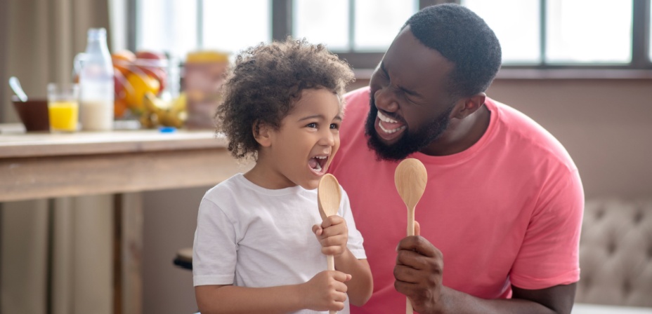 A young dad singing into a spoon with his child having fun. 