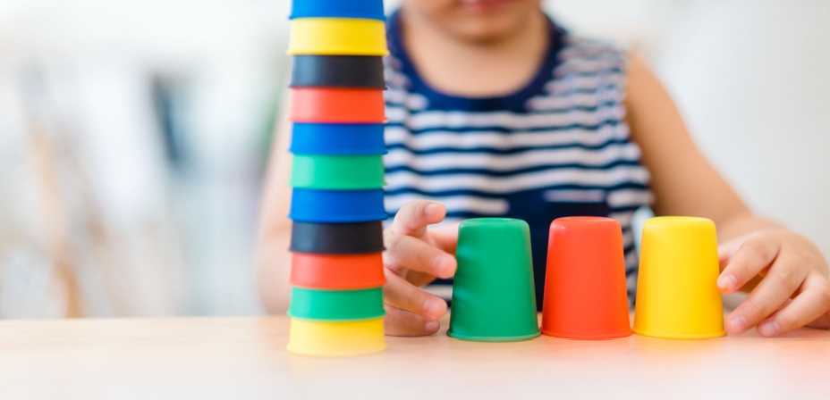 A young child stacking colorful cups. 