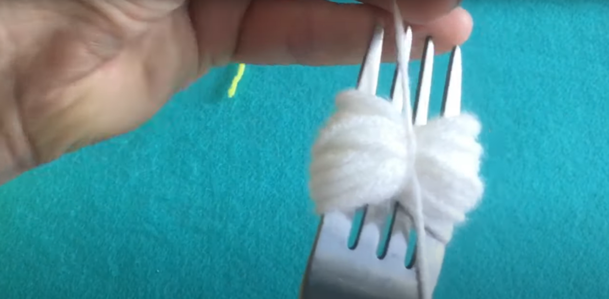 Creating a pom-pom with yarn and a fork. 